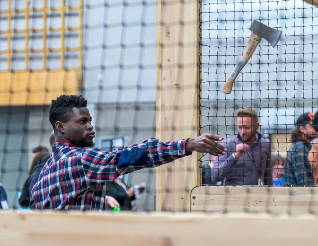 15. AN ATTENDEE SHOWING IMPRESSIVE CONCENTRATION AT THE AX THROWING BOOTH